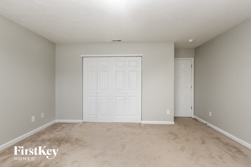 a empty bedroom with two closets and a carpeted floor