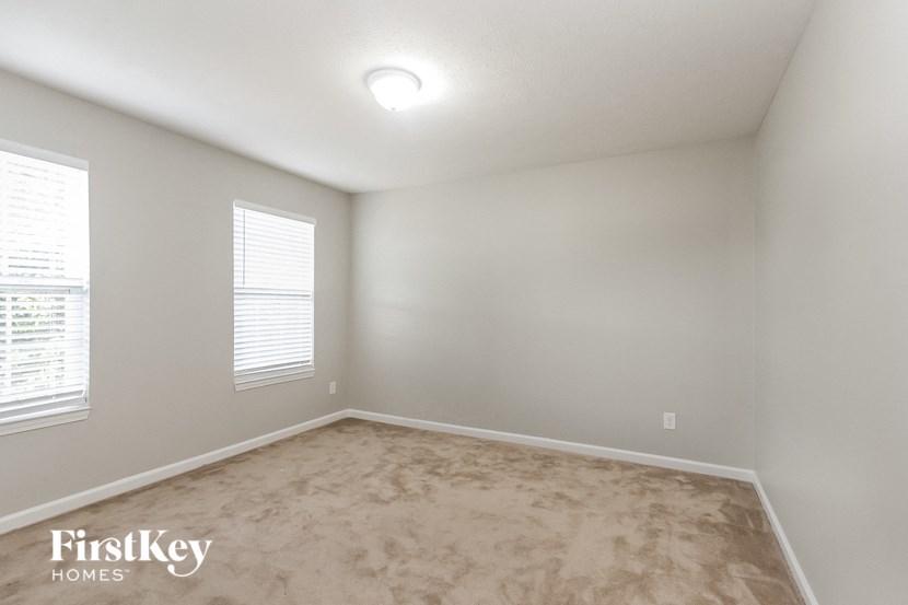 a bedroom with a carpeted floor and two windows