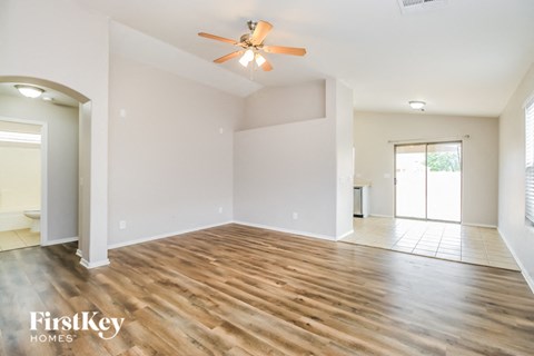 A spacious room with wooden floors and a ceiling fan.