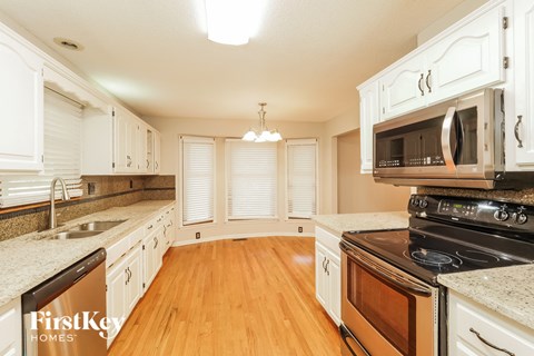 a kitchen with white cabinets and appliances and a wood floor