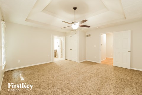 a living room with carpet and a ceiling fan