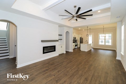 A spacious living room with a fireplace and a ceiling fan.