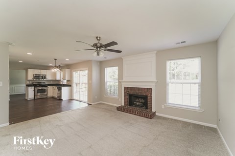 A spacious living room with a fireplace and a ceiling fan.
