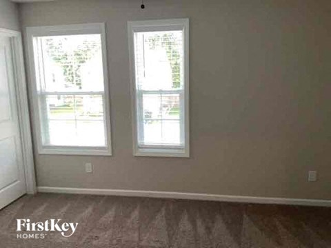 a living room with three windows and a wooden floor