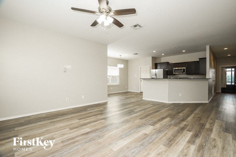 a living room and kitchen with wood flooring and a ceiling fan