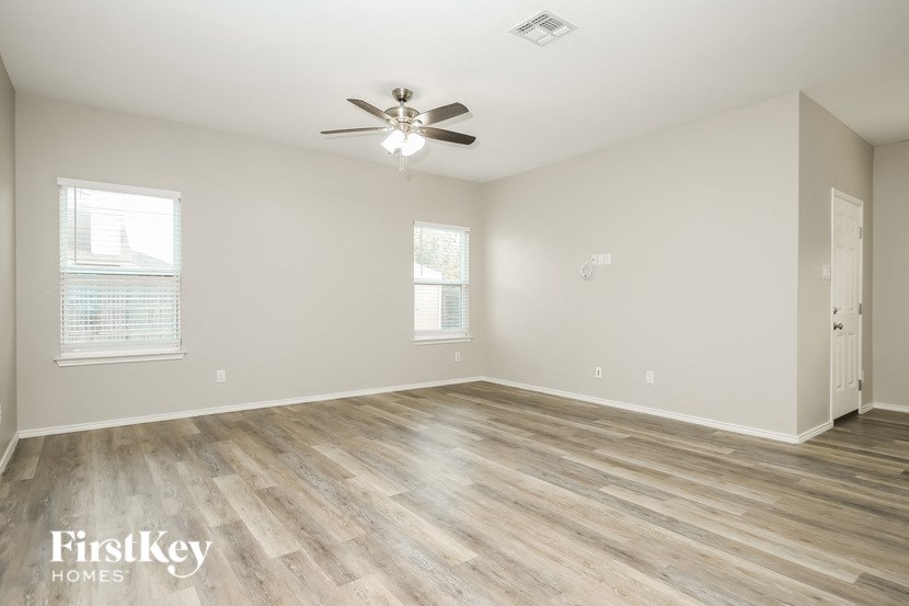 an empty living room with wood flooring and a ceiling fan