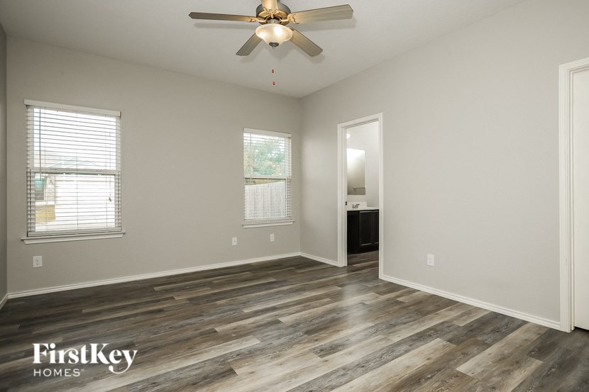 an empty living room with wood flooring and a ceiling fan