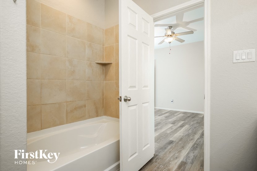 a white bathroom with a tub and a ceiling fan