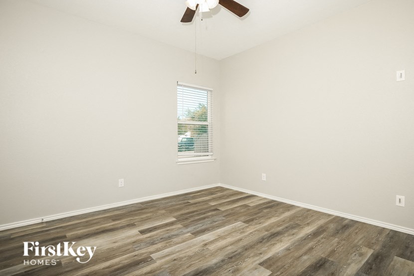 an empty room with wood flooring and a ceiling fan