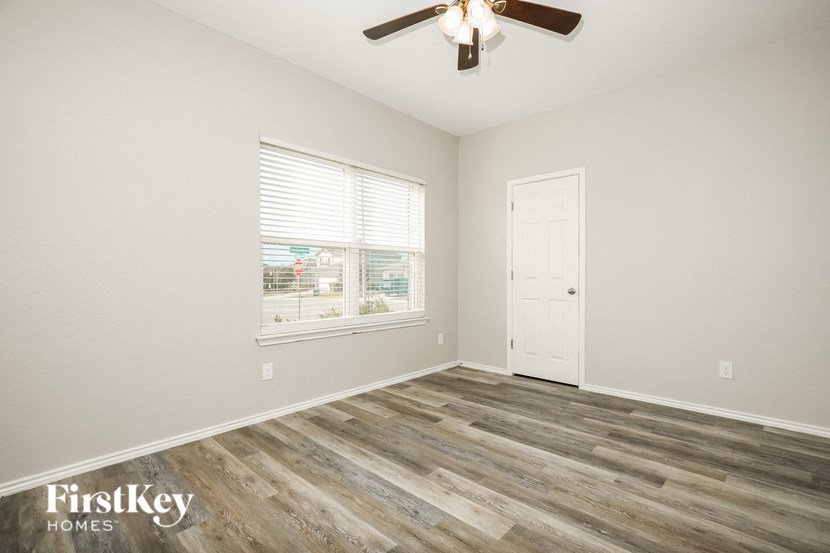 an empty bedroom with a ceiling fan and a window
