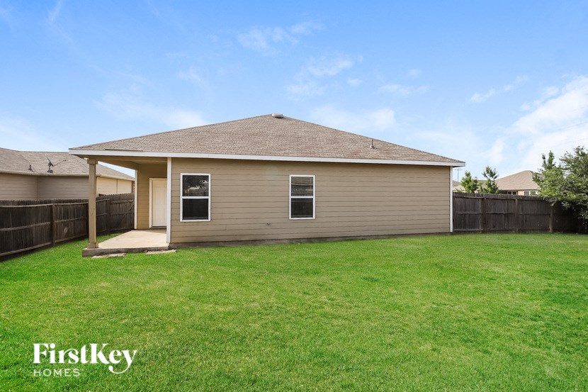 a brown house with a grass yard and a wooden fence