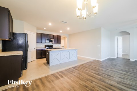 A kitchen with a black fridge and a wooden floor.