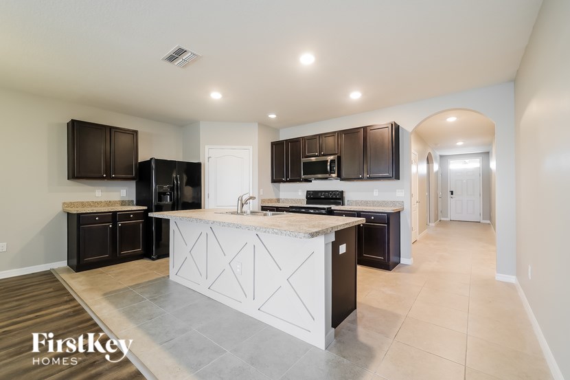 A kitchen with a white island and dark brown cabinets.