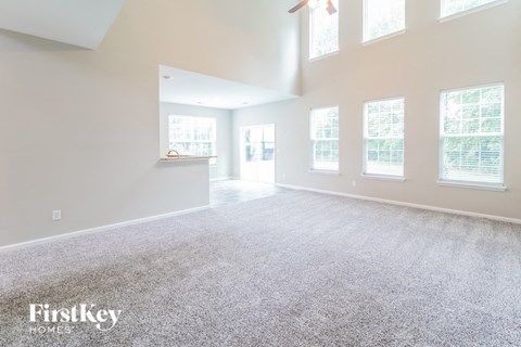 the living room and dining room of an empty home with white walls and carpet