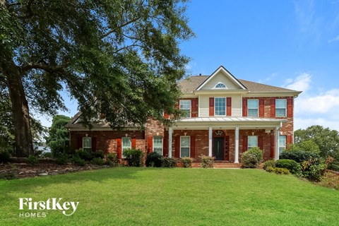 a red brick house with a green lawn and a tree