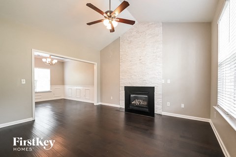A living room with a fireplace and a ceiling fan.