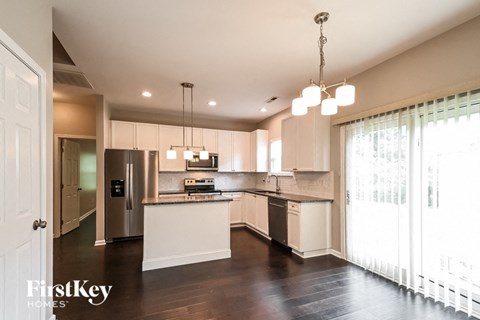 A modern kitchen with a stainless steel refrigerator and white cabinets.