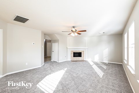 A spacious living room with a fireplace and a ceiling fan.