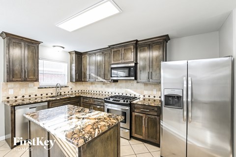 A kitchen with a stove top oven and a refrigerator.