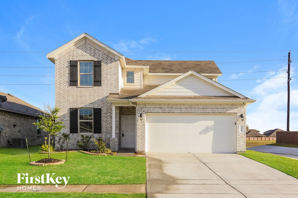 A house with a garage and a driveway in front of it.
