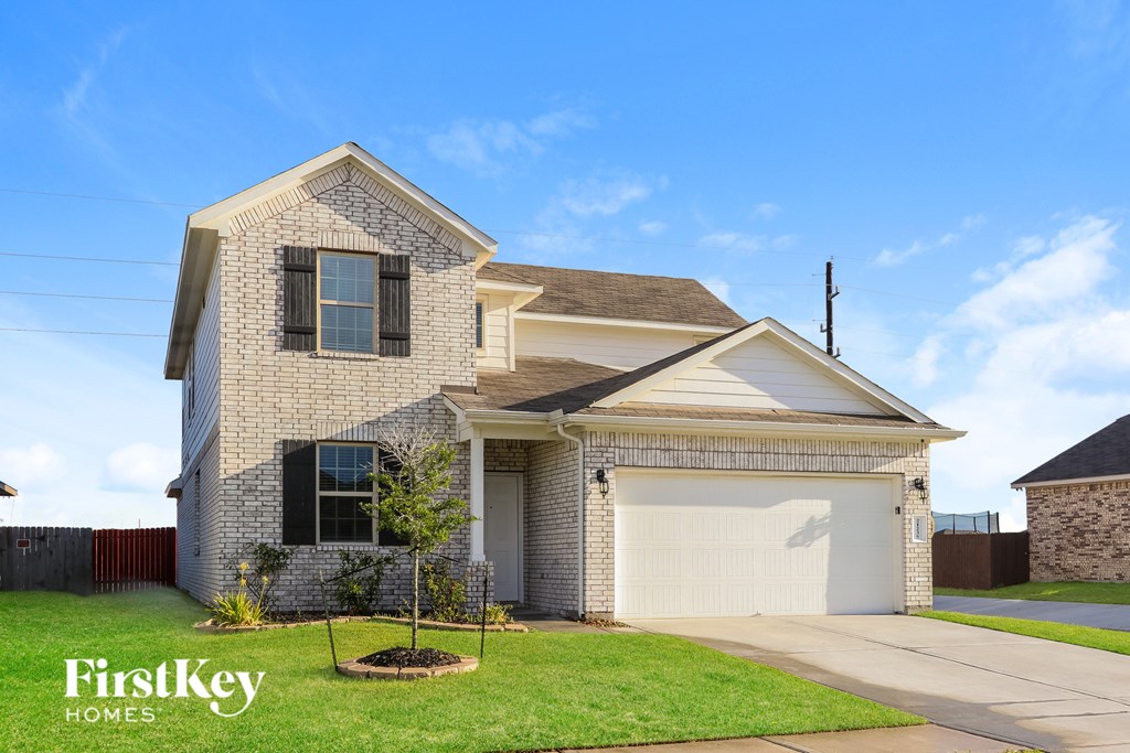 A house with a garage and a tree in front of it.