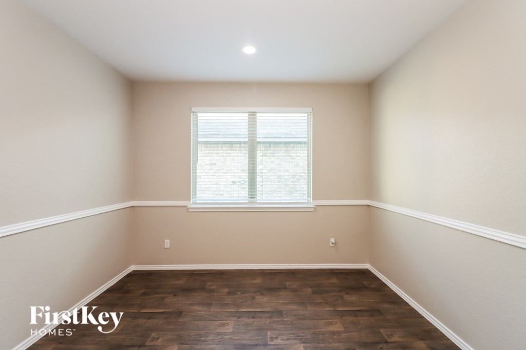 A room with wooden floors and a window with blinds.