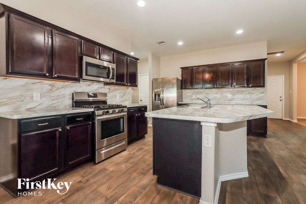 A kitchen with dark brown cabinets and a marble countertop.