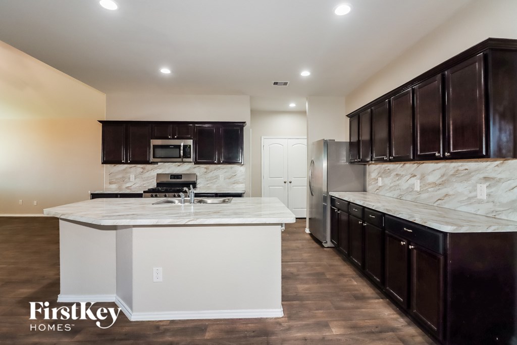 A kitchen with dark brown cabinets and a white island.