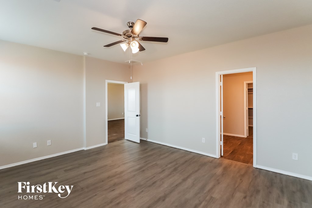 A spacious room with a ceiling fan and wooden flooring.