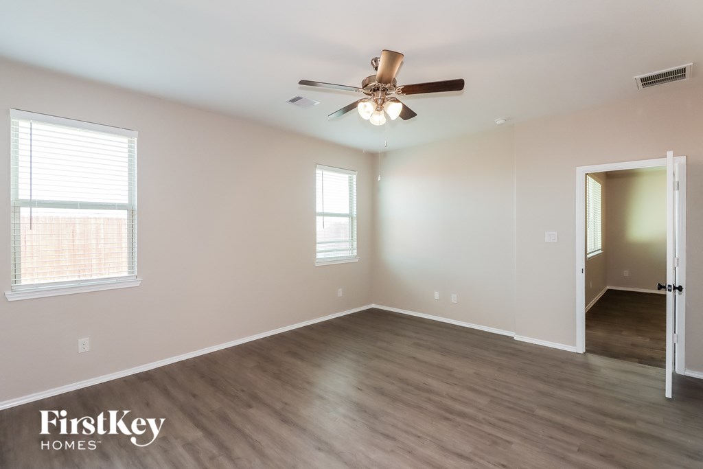 A room with a ceiling fan and two windows.