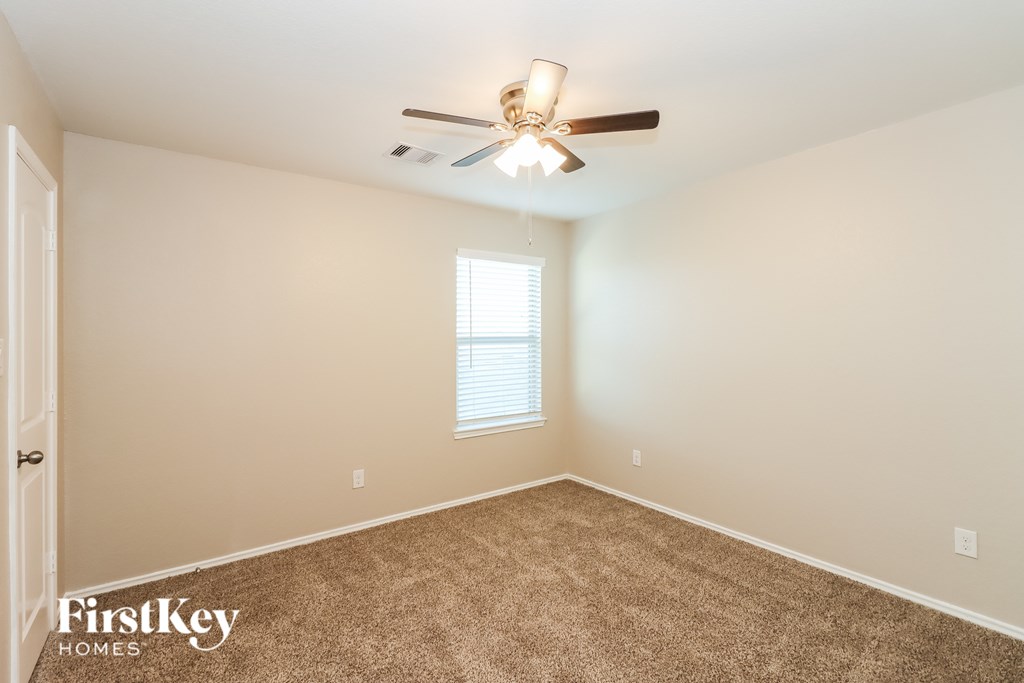 A room with a carpeted floor and a ceiling fan.