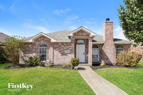 a brick house with a white door and a lawn