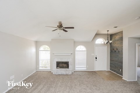an empty living room with a fireplace and a ceiling fan