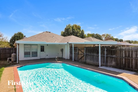 a pool in front of a house with a fence and a swimming pool