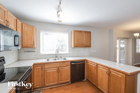A kitchen with wooden cabinets and a black dishwasher.