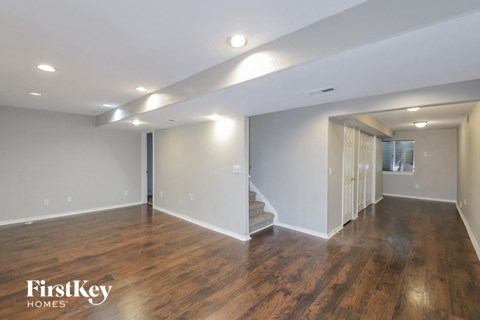 A spacious room with wooden floors and a staircase leading to another room.