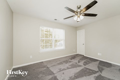 A spacious room with a fan and a window with blinds.