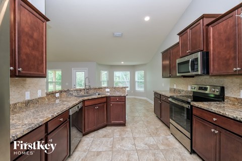 A kitchen with brown cabinets and a Firstkey Homes logo.
