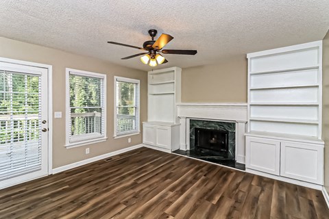 an empty living room with a fireplace and a ceiling fan
