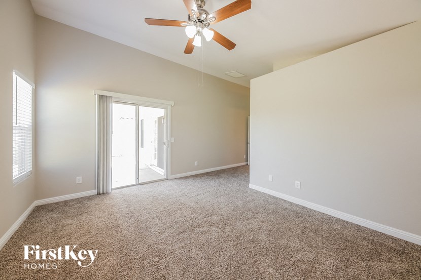 a spacious living room with carpet and a ceiling fan