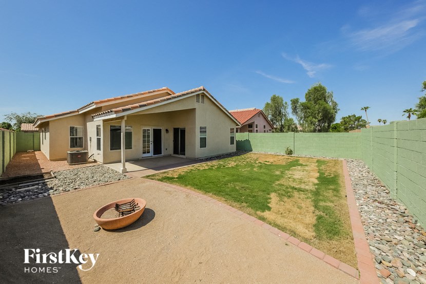 a house with a yard and a patio and a green fence