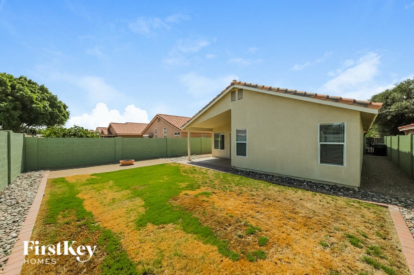 a backyard with a green lawn and a white house