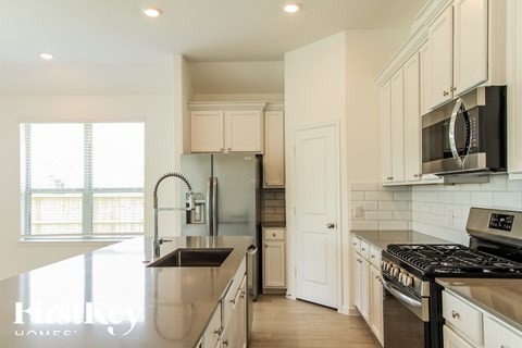 A kitchen with white cabinets and a black stove top oven.