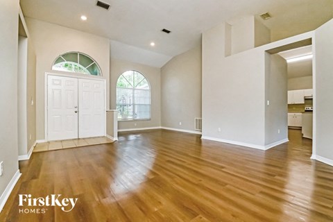 an empty living room with a hardwood floor and a white door