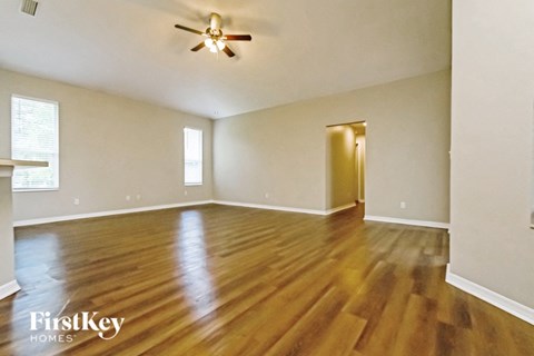 an empty living room with wood flooring and a ceiling fan