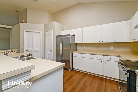 an empty kitchen with white cabinets and a stainless steel refrigerator