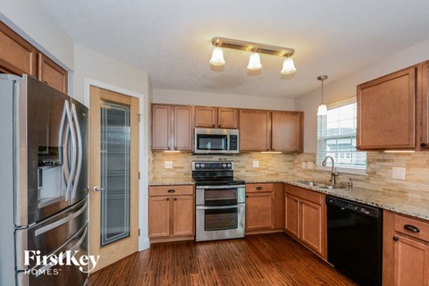 A kitchen with wooden cabinets and a black dishwasher.