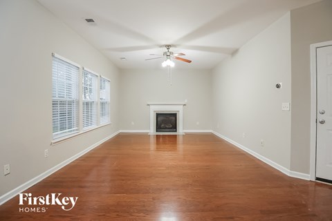 A spacious room with a fireplace and wood flooring.