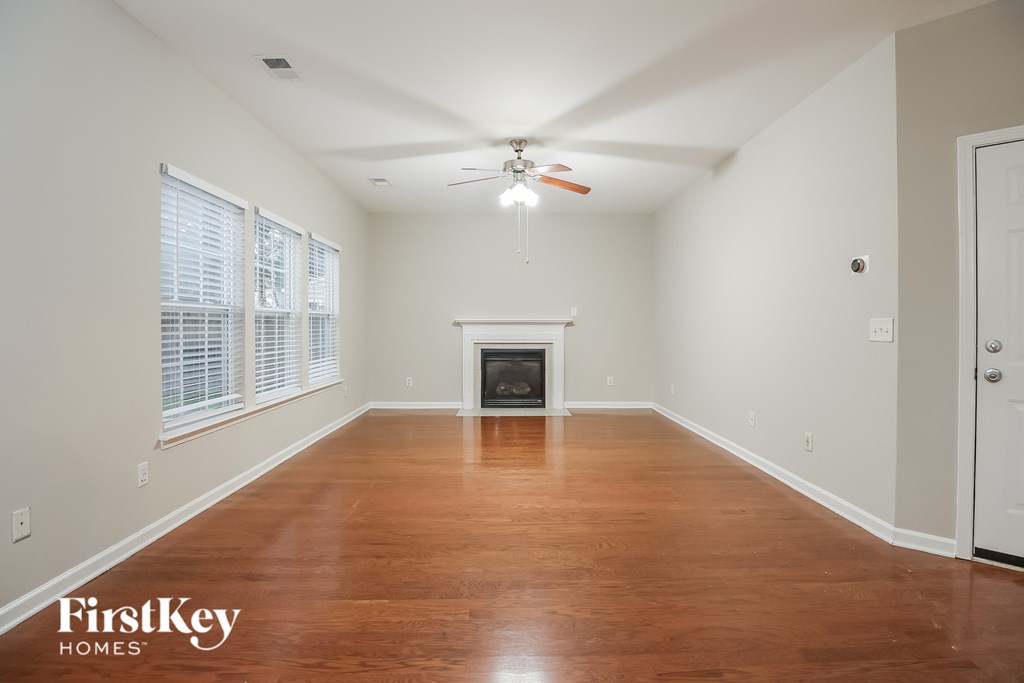 A spacious room with a fireplace and wood flooring.