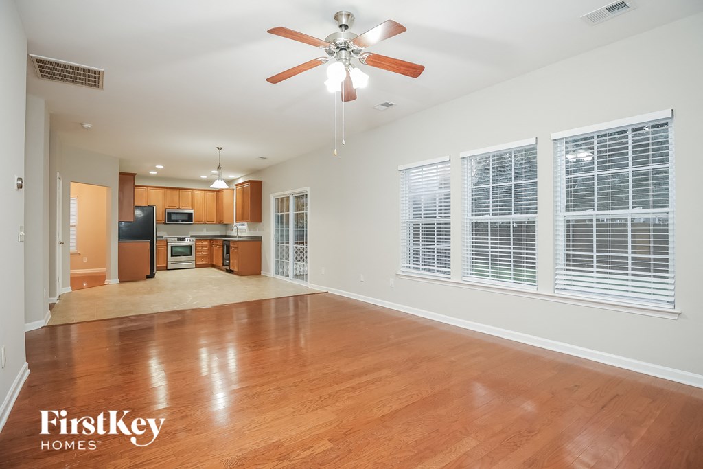 A spacious room with a ceiling fan and wooden flooring.